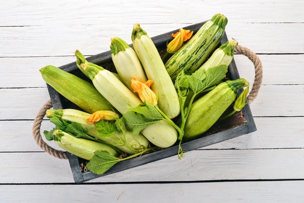 squash marrow zucchini in a wooden box on a white table top view copy space - Цукини с грибами