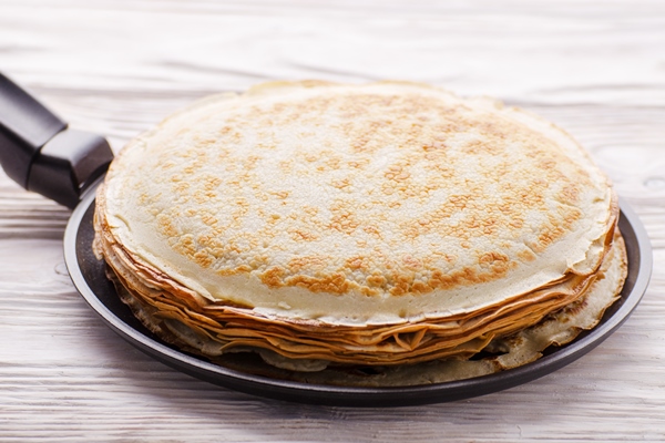 stack of french crepes in frying pan on wooden kitchen table - Постные блинцы на фасолевом отваре