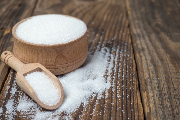 stack of sugar cubes and granulated sugar in a wooden scoop - Цукаты из сливы