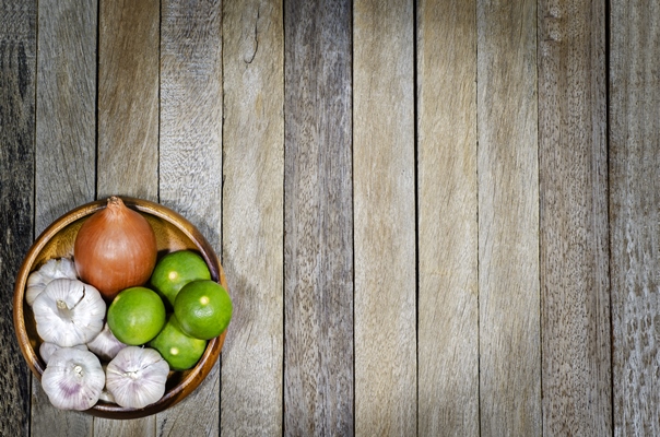 still life natural organic vegetable onions garlic lemon in wooden bowl on old wood plank background texture edge darken style - Салат «Освежающий»