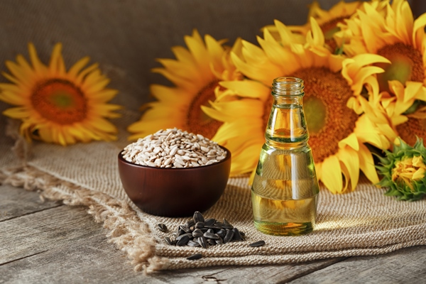sunflower oil in a glass bottle with seeds in a cup and flowers on a wooden table - Лествицы ржаные