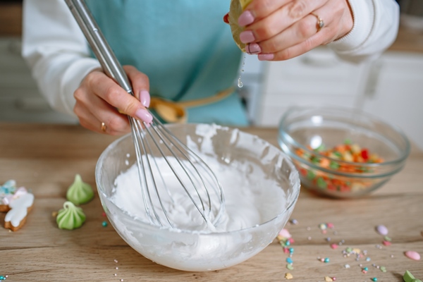 the smiling woman cook whips up the icing for the easter cake with a whisk and squeezes a lemon into it - Баба кружевная