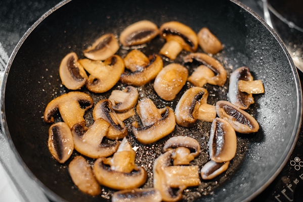 thinly sliced fresh raw mushrooms are fried in a pan close up healthy diet - Салат с грибами на зиму