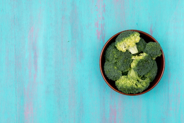 top view fresh green broccoli on plate on blue wooden surface - Особенности диеты при аллергических заболеваниях