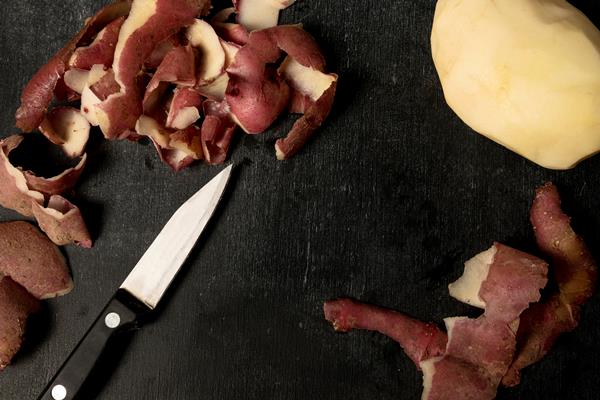 top view of peeled potato with knife - Постные дрожжевые блины с картофелем