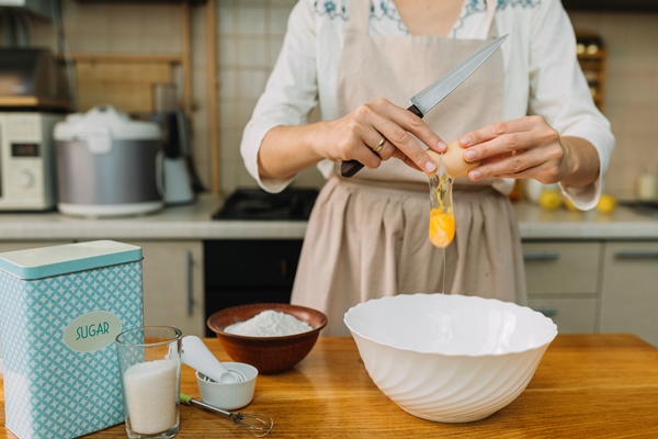 woman breaks egg for making pie in kitchen - Шоколадные блинцы