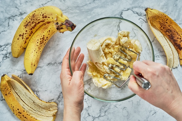 woman hand mashing up several bananas to bake into a banana bread - Кексы из бананов диетические