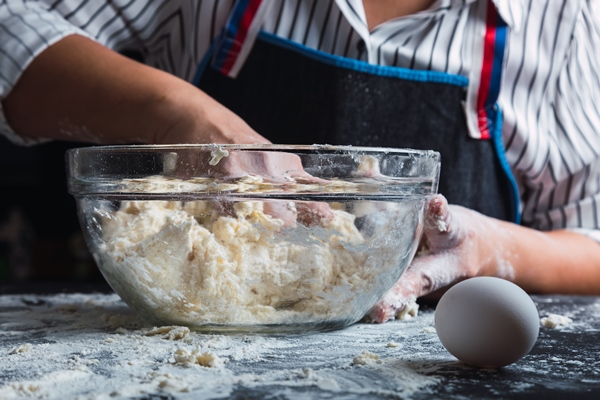 woman kneading dough in glass bowl - Кулич заварной