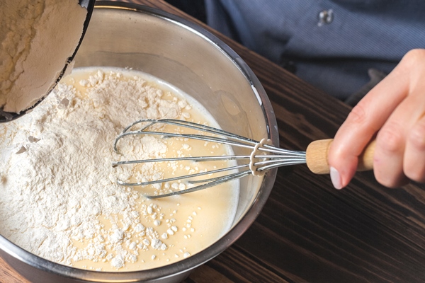 woman kneads dough in a metal bowl preparation of dough for baking pancakes selective focus 1 - Постные блинчики со свёклой и орешками