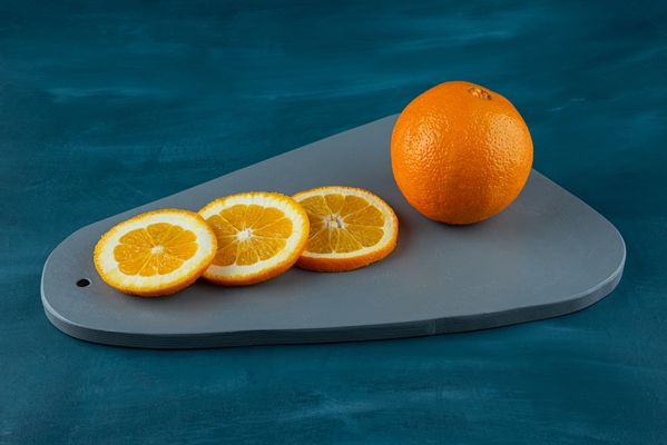 wooden board of sliced juicy oranges on blue surface - Абрикосовый компот с апельсинами