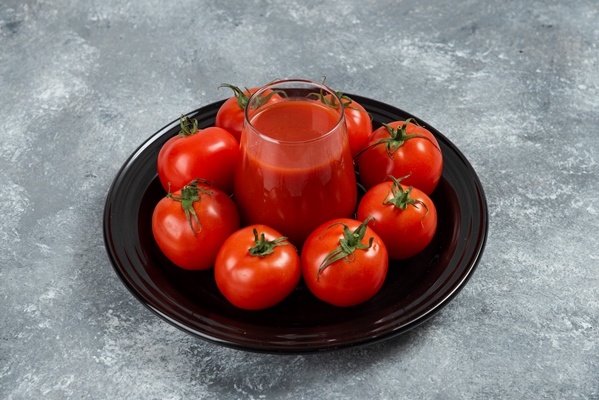 a glass cup of tomato juice on a black plate - Баклажаны, тушённые со свежими помидорами и луком