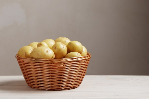 basket full of fresh young potatoes on a wooden table with place for - Тушёный картофель в томатном соусе