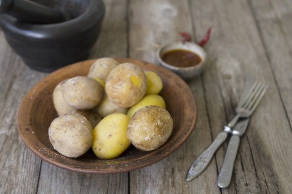 boiled potatoes in their skins whole with red pepper salt and spicy sauce on clay plate old wooden table rustic style close up copy space top view - Зразы картофельные с грибами