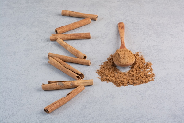 cinnamon sticks and blended powder in a wooden spoon - Начинка для сладкого пирога с рисом