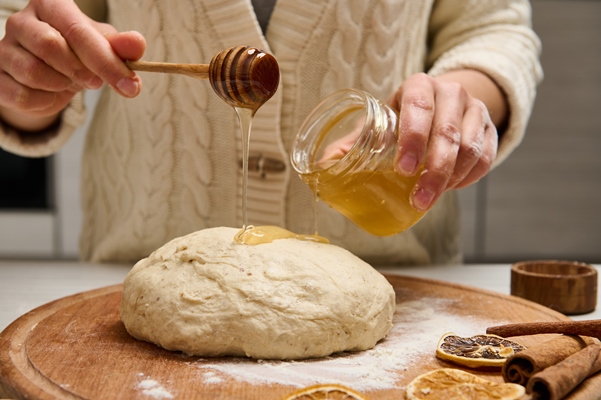 close up woman preparing gingerbread dough holding a wooden stick and pouring some honey on pastry - Штрудели с яблоками