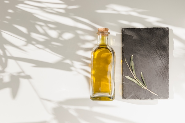 closed olive oil bottle and twig on stone plate over the plain background - Крапивный соус 