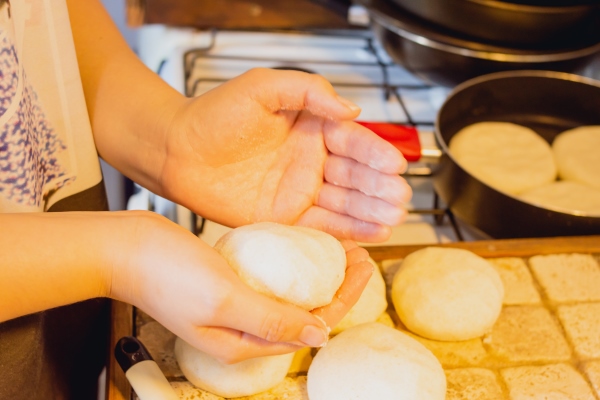 closeup of woman in the kitchen with a ball of dough in her hands preparing an arepa on the counter - Постное тесто для сладких жареных пирожков