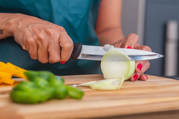 closeup of woman using a knife and cutting onion closeup cutting onion and vegetables - Картофельный салат с рисом и рыбой