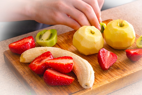 cooking fruit salad in the kitchen banana strawberries kiwi apples on the kitchen board - Фруктовый салат, постный стол