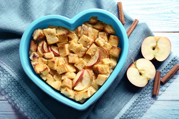 delicious bread pudding with apples in heart shape bowl on napkin - Шарлотка из яблок с гренками