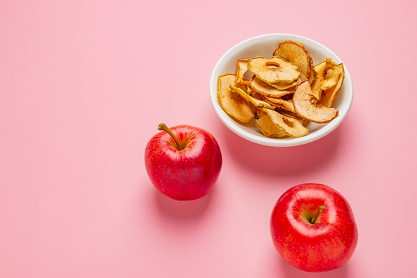 dried apples chips in ceramic bowl with fresh red apples on table - Тушёные яблоки
