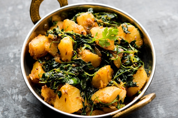 fenugreek potato sabzi or aloo methi masala is healthy indian cuisine served in a bowl or karahi selective focus - Сныть с тушёным картофелем