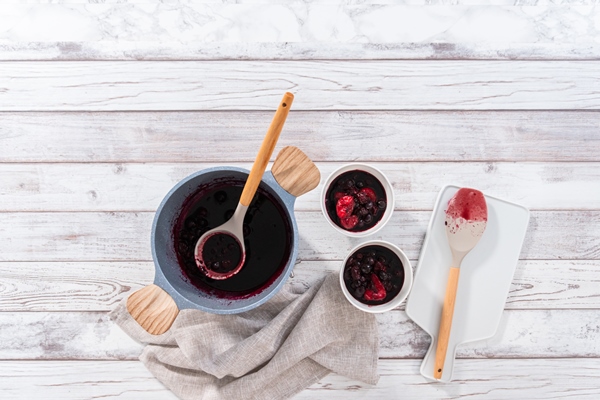 flat lay preparing mixed berry compote from frozen berries in a nonstick cooking pot - Напиток клюквенный с мёдом
