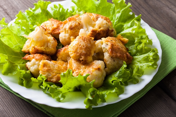 fried cauliflower closeup on the plate on a table - Цветная капуста с сухарями или соусом