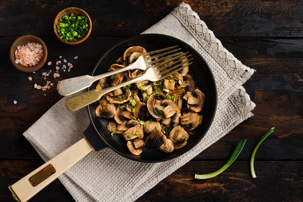 fried champignon mushrooms in a cast iron old pan on an old dark wooden rustic for frying - Кислый грибной суп, постный стол