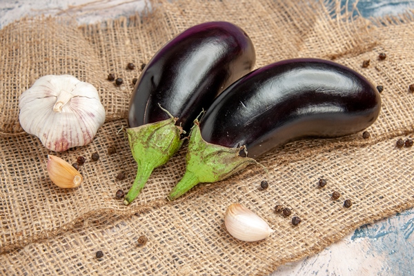 front view aubergines garlic black pepper on straw tablecloth - Баклажаны фаршированные (по-румынски), постный стол