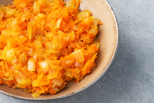 fry grated carrots and chopped onions with oil in a frying pan gray concrete table copy space - Бульон грибной постный