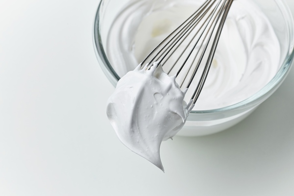 glass bowl of whipped egg whites cream on white kitchen table background top view - Безе яблочное
