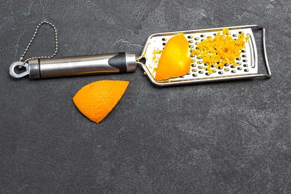 grated orange peel on grater black background top view copy space - Рис холодный с апельсинами