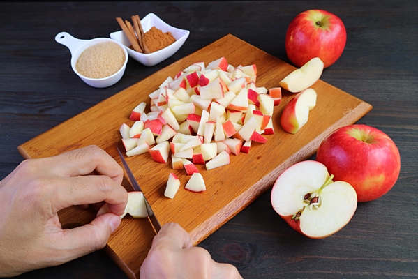 hand dicing fresh apples on cutting board for making apple compote - Начинка из яблок и риса