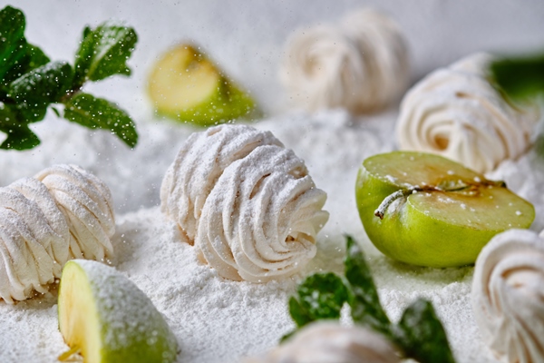 homemade handmade apple marshmallows on a background of icing sugar dessert in the snow sweetness is decorated with apples and mint - Безе яблочное