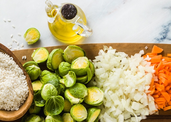 ingredients for risotto with brussels sprouts on a wooden cutting board and marble table - Плов с капустой