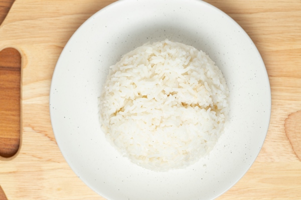 jasmine rice is arranged in a round shape on a white bowl that is placed on a wooden - Пудинг из риса с черносливом