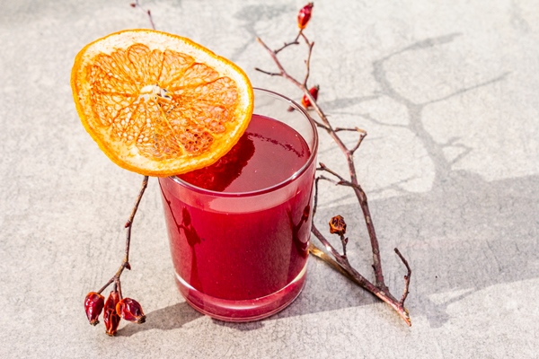 natural fresh organic smoothies made of viburnum wild rose and grapefruit in a glass on a stone surface dog rose twigs dried grapefruit - Кисель из плодов шиповника