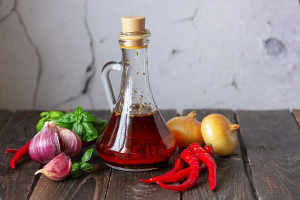 olive oil with spices in a bottle on a wooden table next to chili garlic onion basil - Салат картофельный с чесноком