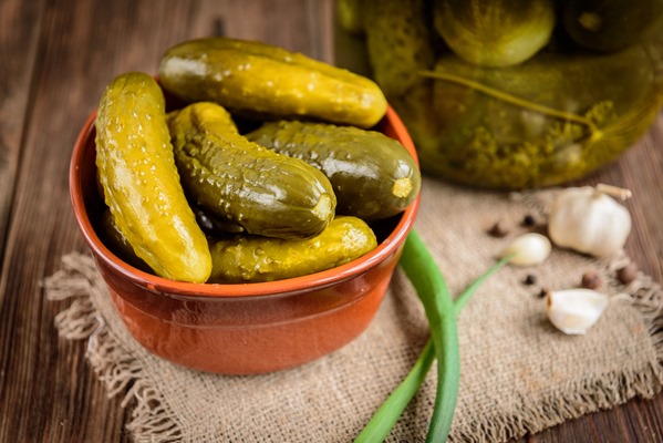 pickled cucumbers in bowl on wooden rustic table with garlic and jar of pickles - Винегрет с сельдью