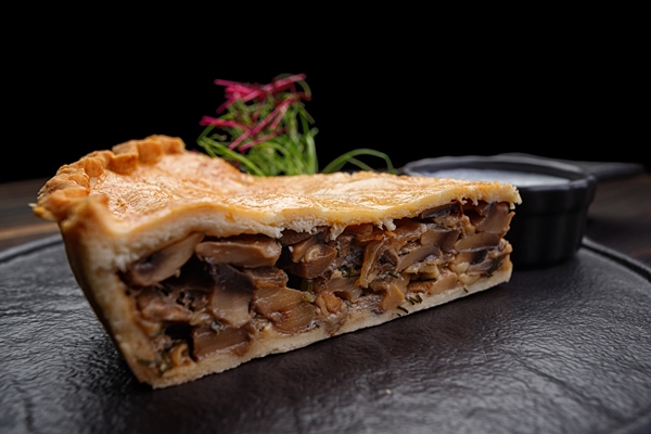 piece of baked pie with mushrooms and sauce - Пирог с солёными грибами