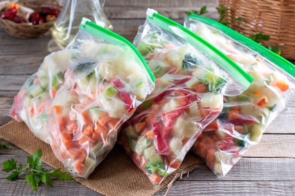 plastic bags with different frozen vegetables on wooden table - Сырный суп