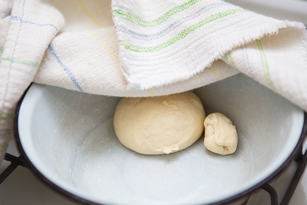 preparation of dough for making dumplings ravioli manti dumplings dough in a plate under a towel - Плацинды постные