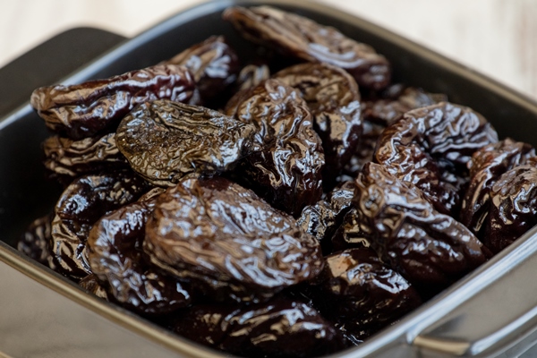 prunes group in wooden bowl dried prunes in a plate plate food black - Тушёный картофель с черносливом и изюмом