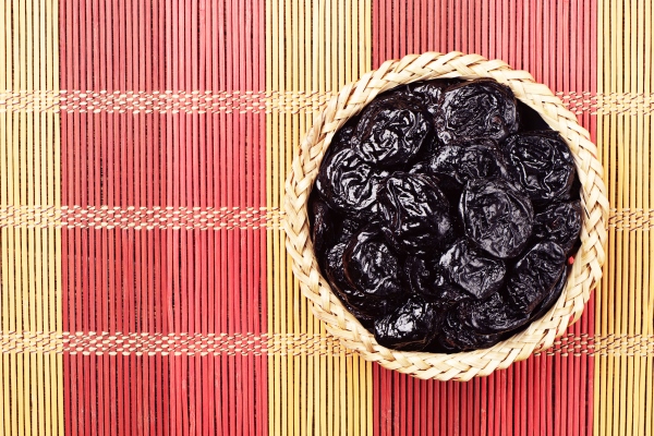 prunes in wicker bowl on bamboo napkin - Постный рис с черносливом