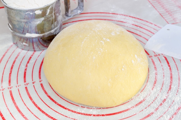 raw yeast dough on the floured silicone baking mat with markings on the kitchen table - Пирог с рыбным фаршем и рыбой