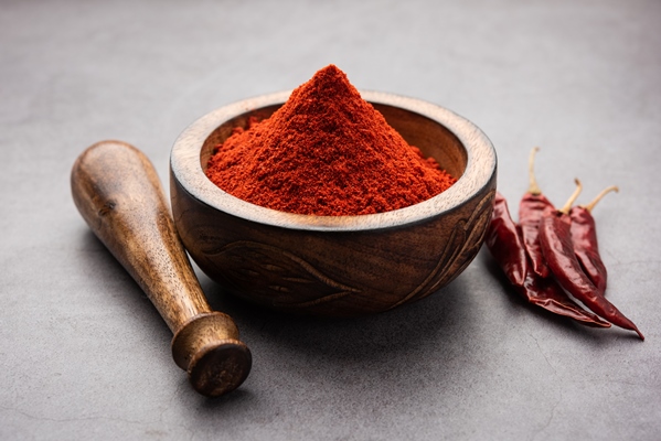 red chilli or lal mirchi or mirch with powder in a bowl or mortar over moody background selective focus - Тушёный картофель в томатном соусе