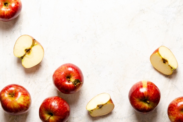 red whole and sliced apples on a light background - Блинчики с яблоками