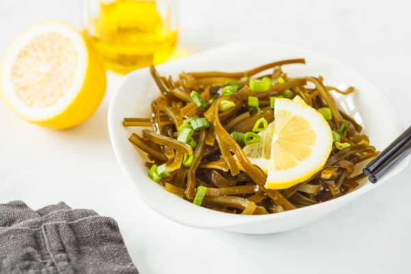 sea kale kelp salad with oil in a white plate white background healthy vegan food concept - Маринованный лук с морской капустой