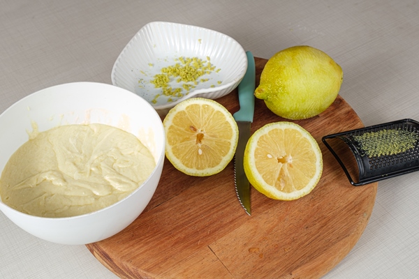 sicilian lemon sliced in half next to a pot of white chocolate ganache lemon zest and a metal grater - Оладьи с корицей и лимонной цедрой